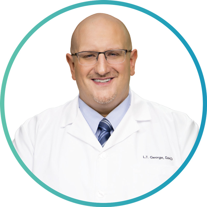 L.T. George, DMD, smiling in a white coat, representing Siouxland Oral Surgery, promoting dental education and events for professionals.